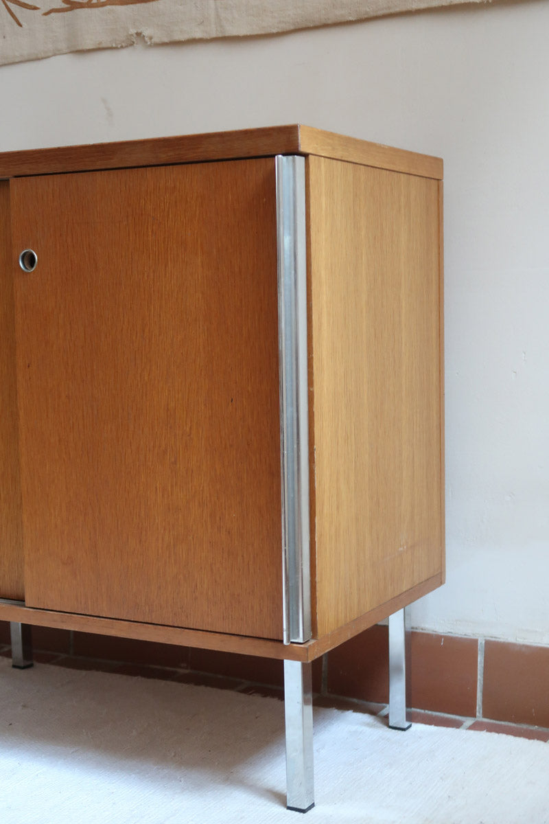 Meuble bas années 70 en bois avec piètement et montants en métal chromé, portes coulissantes et étagère intérieure.