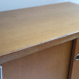 Meuble bas années 70 en bois avec piètement et montants en métal chromé, portes coulissantes et étagère intérieure.