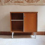 Meuble bas années 70 en bois avec piètement et montants en métal chromé, portes coulissantes et étagère intérieure.