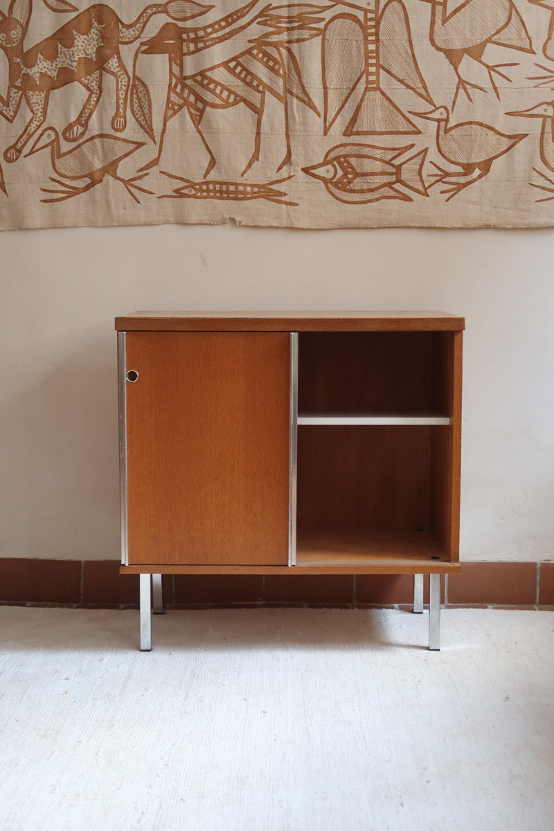 Meuble bas années 70 en bois avec piètement et montants en métal chromé, portes coulissantes et étagère intérieure.
