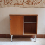 Meuble bas années 70 en bois avec piètement et montants en métal chromé, portes coulissantes et étagère intérieure.