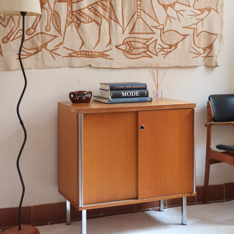 Meuble bas années 70 en bois avec piètement et montants en métal chromé, portes coulissantes et étagère intérieure.