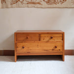 Commode basse en pin massif années 70 à trois tiroirs avec assemblages à queues d’aronde visibles et poignées rondes en bois.