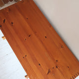 Commode basse en pin massif années 70 à trois tiroirs avec assemblages à queues d’aronde visibles et poignées rondes en bois.