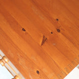 Commode basse en pin massif années 70 à trois tiroirs avec assemblages à queues d’aronde visibles et poignées rondes en bois.
