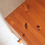 Commode basse en pin massif années 70 à trois tiroirs avec assemblages à queues d’aronde visibles et poignées rondes en bois.
