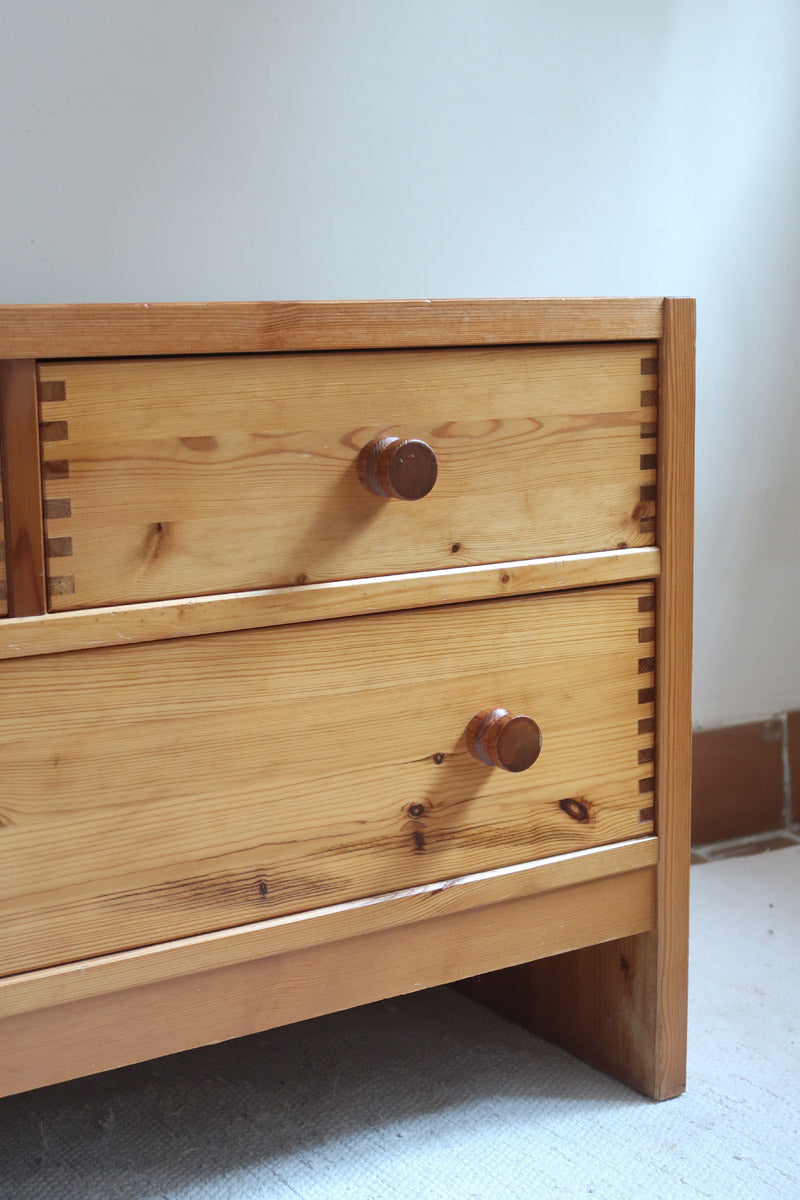 Commode basse en pin massif années 70 à trois tiroirs avec assemblages à queues d’aronde visibles et poignées rondes en bois.