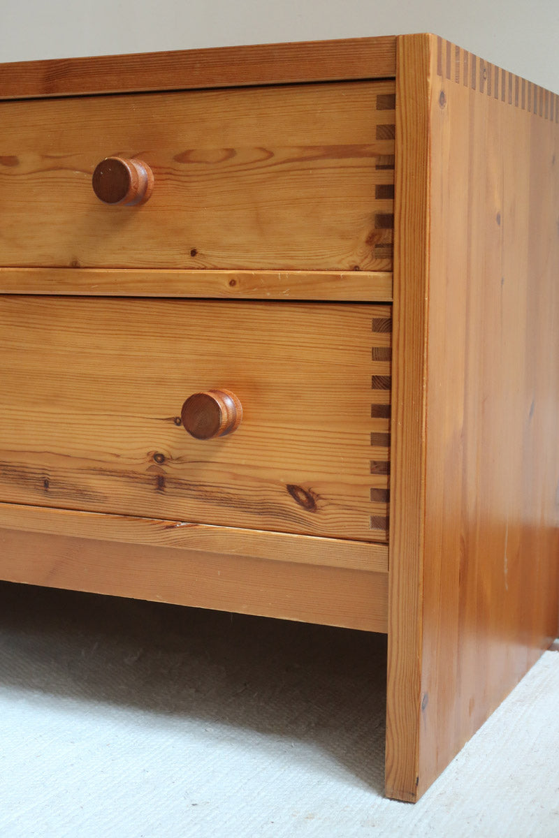 Commode basse en pin massif années 70 à trois tiroirs avec assemblages à queues d’aronde visibles et poignées rondes en bois.