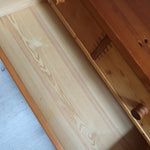 Commode basse en pin massif années 70 à trois tiroirs avec assemblages à queues d’aronde visibles et poignées rondes en bois.
