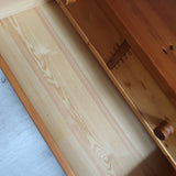Commode basse en pin massif années 70 à trois tiroirs avec assemblages à queues d’aronde visibles et poignées rondes en bois.