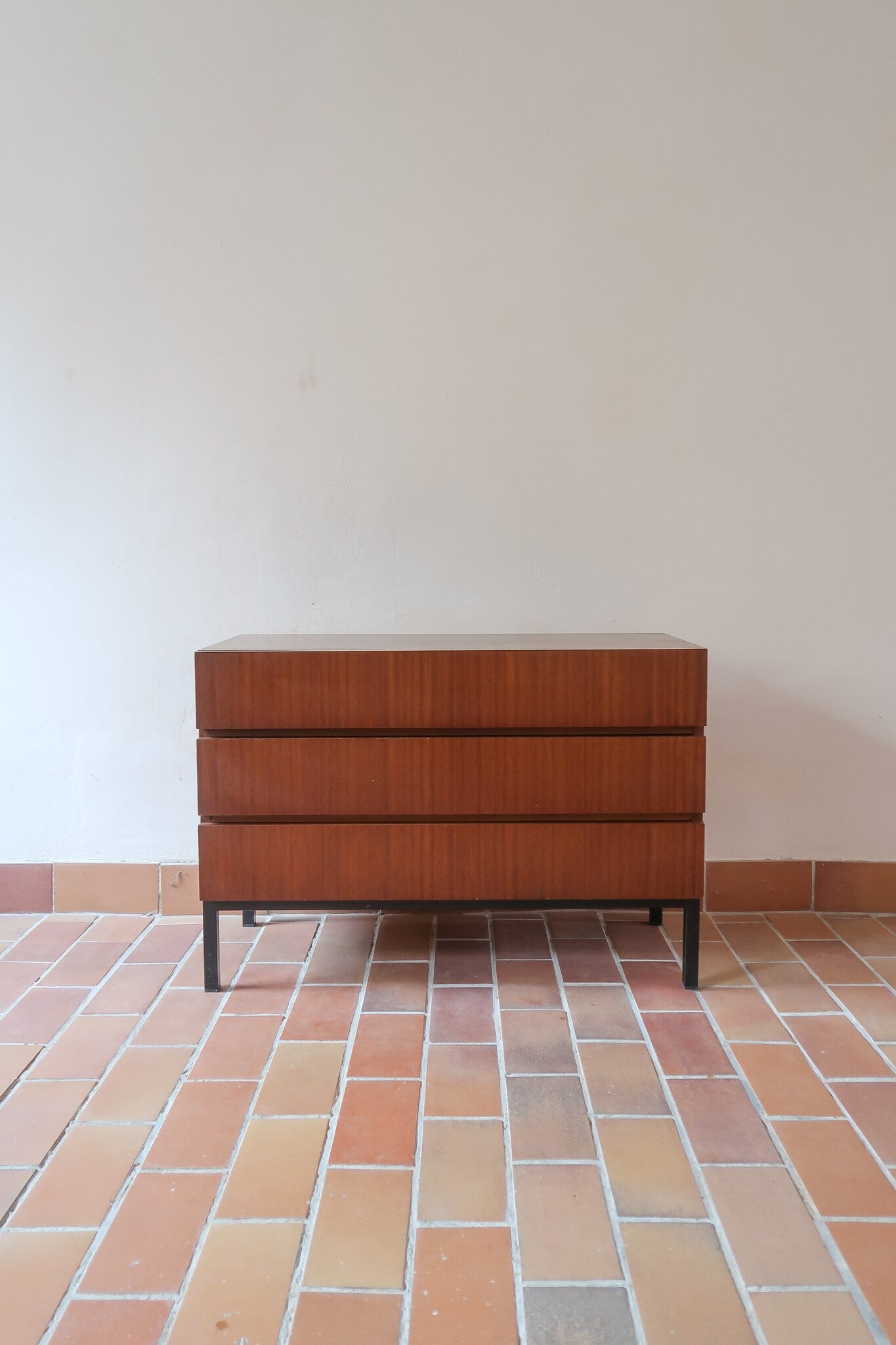 Commode vintage 3 tiroirs en teck années 60, façades pleines à prise de main creusée, piétement fin en métal laqué noir, style scandinave