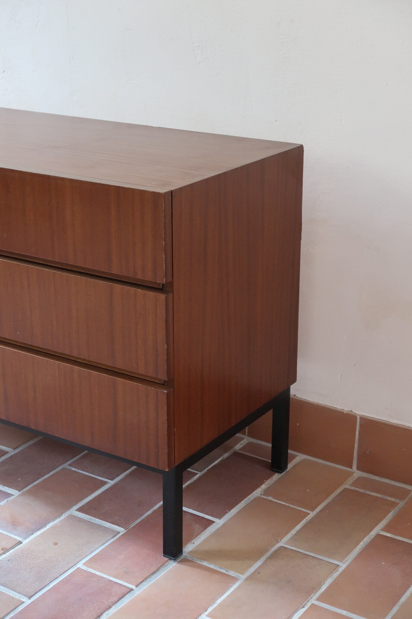 Commode vintage 3 tiroirs en teck années 60, façades pleines à prise de main creusée, piétement fin en métal laqué noir, style scandinave