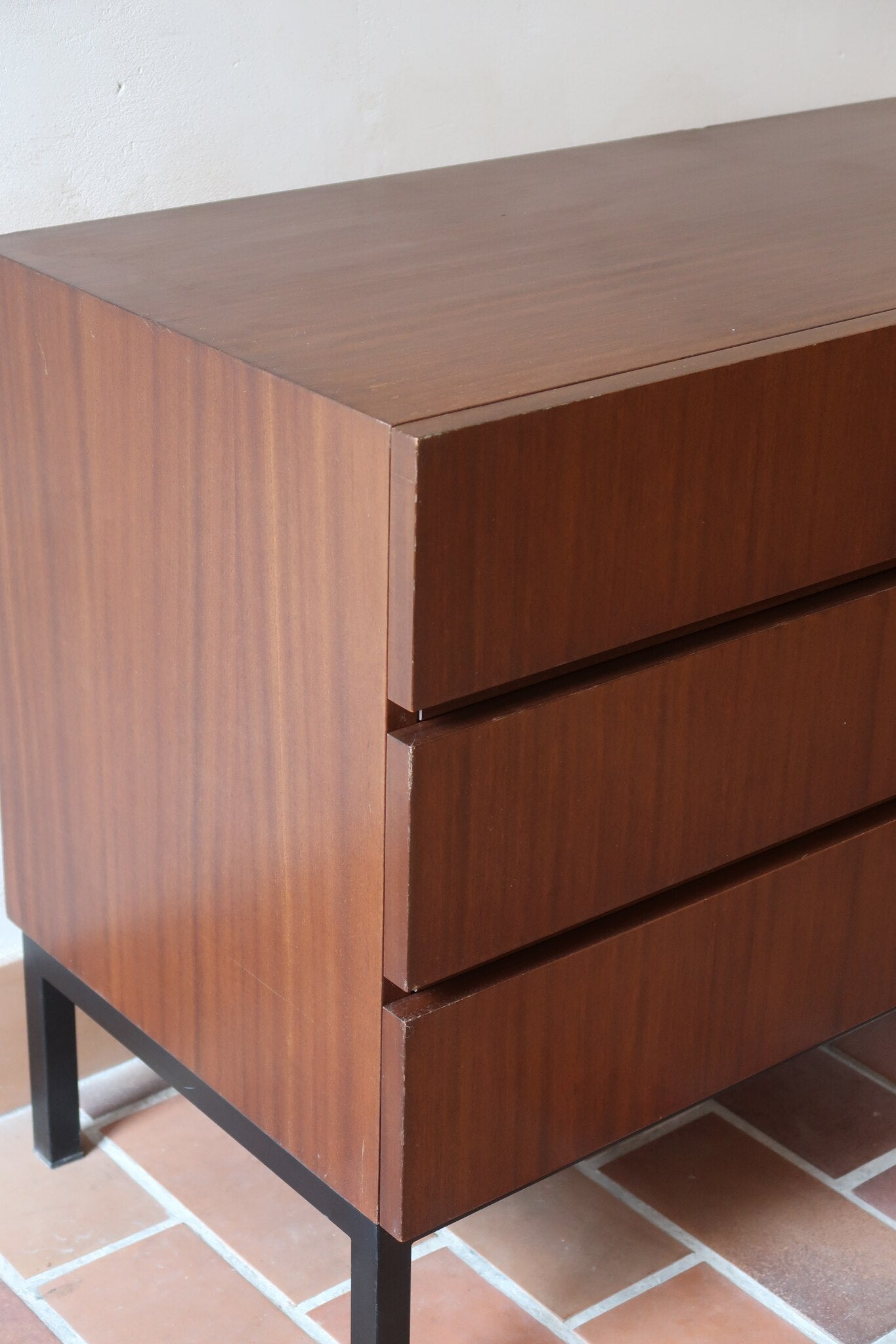 Commode vintage 3 tiroirs en teck années 60, façades pleines à prise de main creusée, piétement fin en métal laqué noir, style scandinave