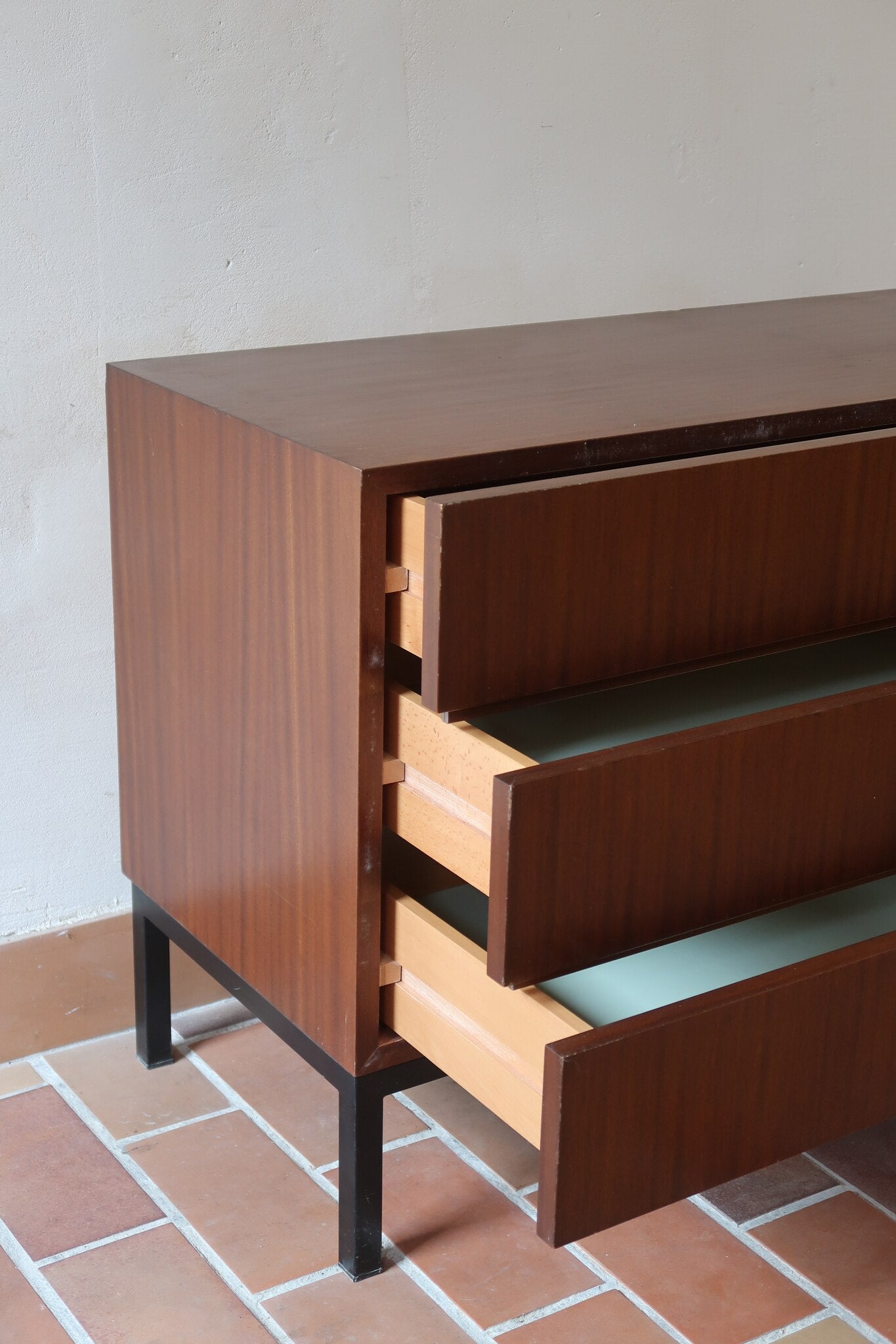 Commode vintage 3 tiroirs en teck années 60, façades pleines à prise de main creusée, piétement fin en métal laqué noir, style scandinave