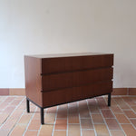 Commode vintage 3 tiroirs en teck années 60, façades pleines à prise de main creusée, piétement fin en métal laqué noir, style scandinave