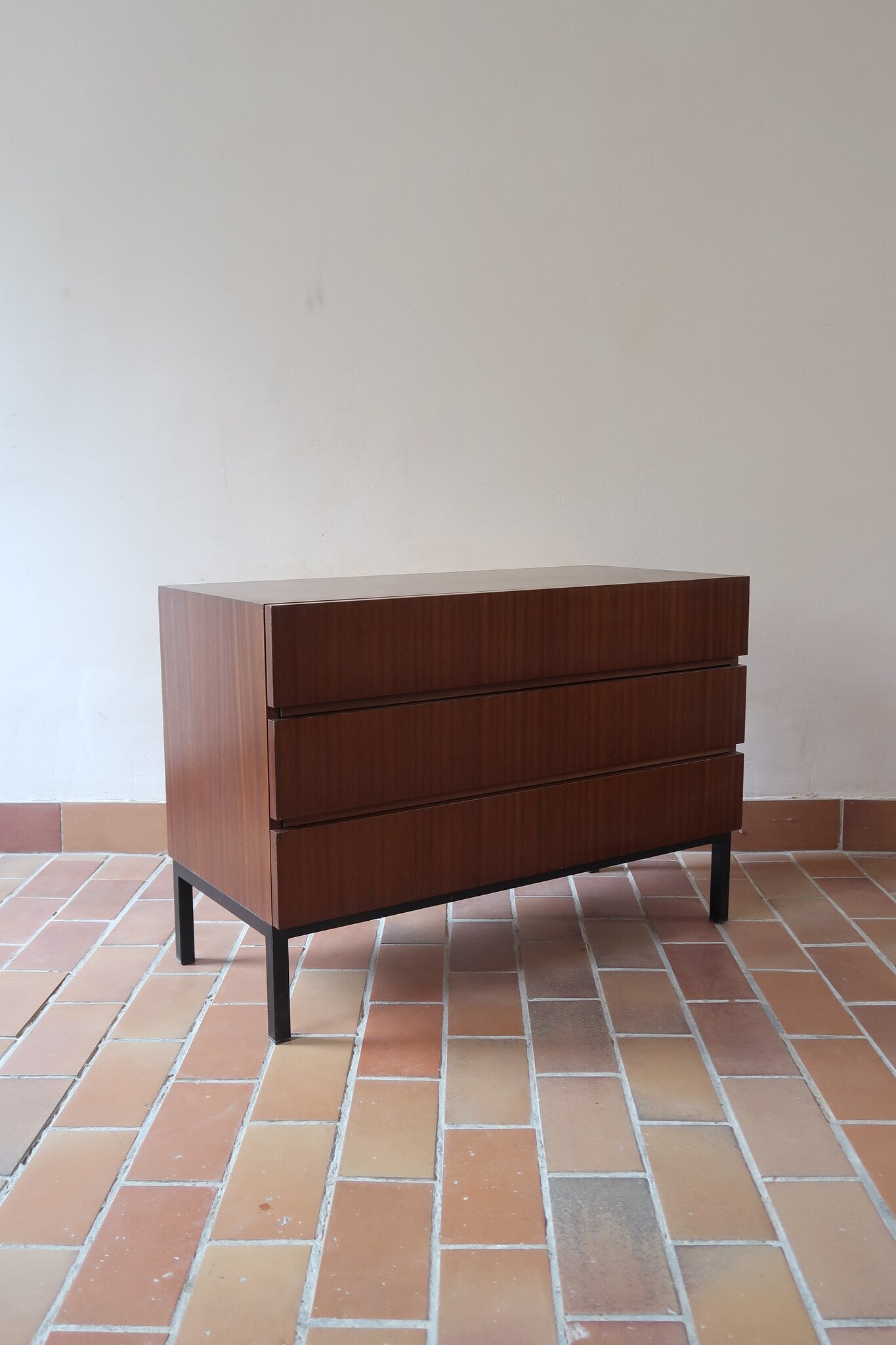 Commode vintage 3 tiroirs en teck années 60, façades pleines à prise de main creusée, piétement fin en métal laqué noir, style scandinave