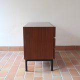 Commode vintage 3 tiroirs en teck années 60, façades pleines à prise de main creusée, piétement fin en métal laqué noir, style scandinave