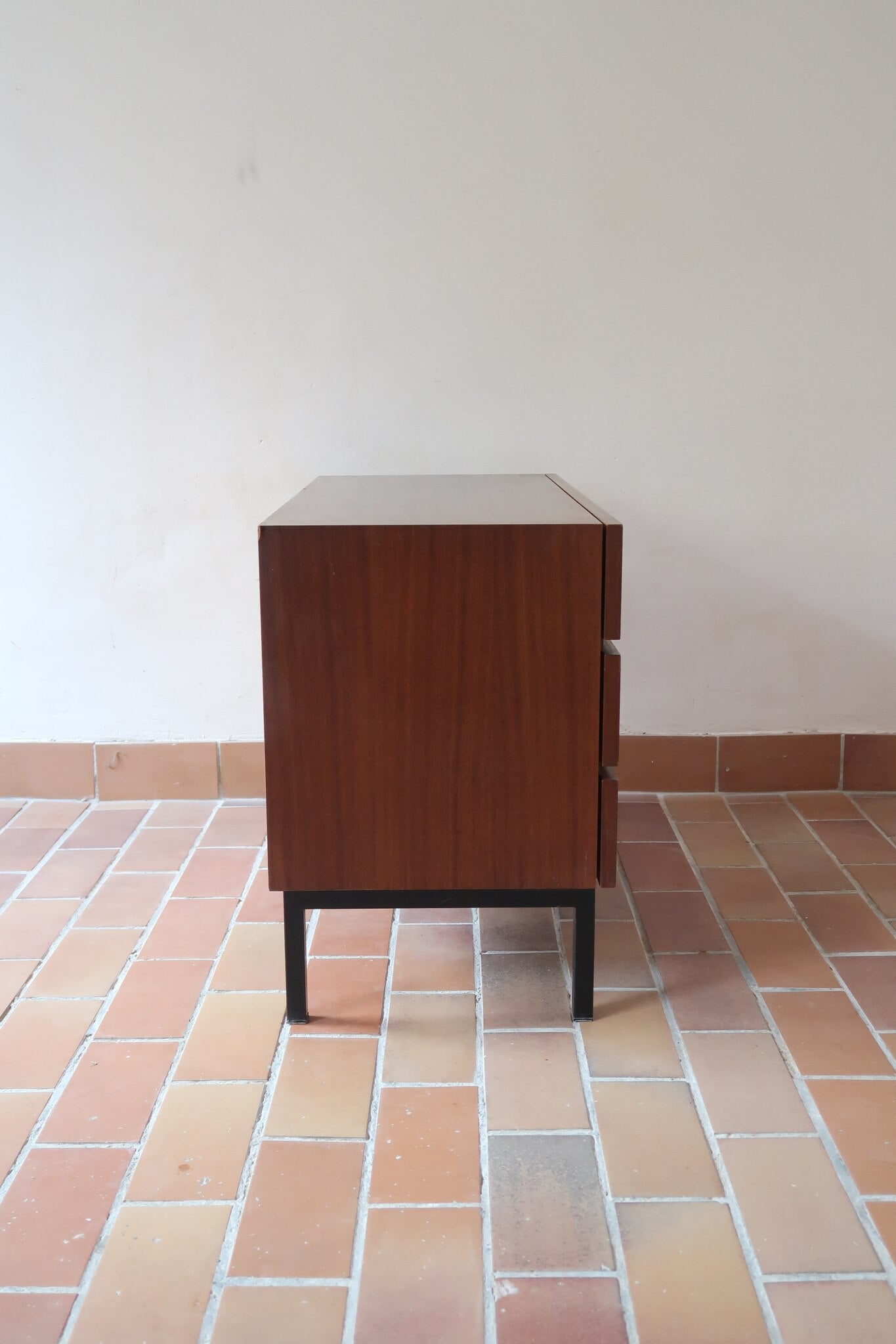 Commode vintage 3 tiroirs en teck années 60, façades pleines à prise de main creusée, piétement fin en métal laqué noir, style scandinave