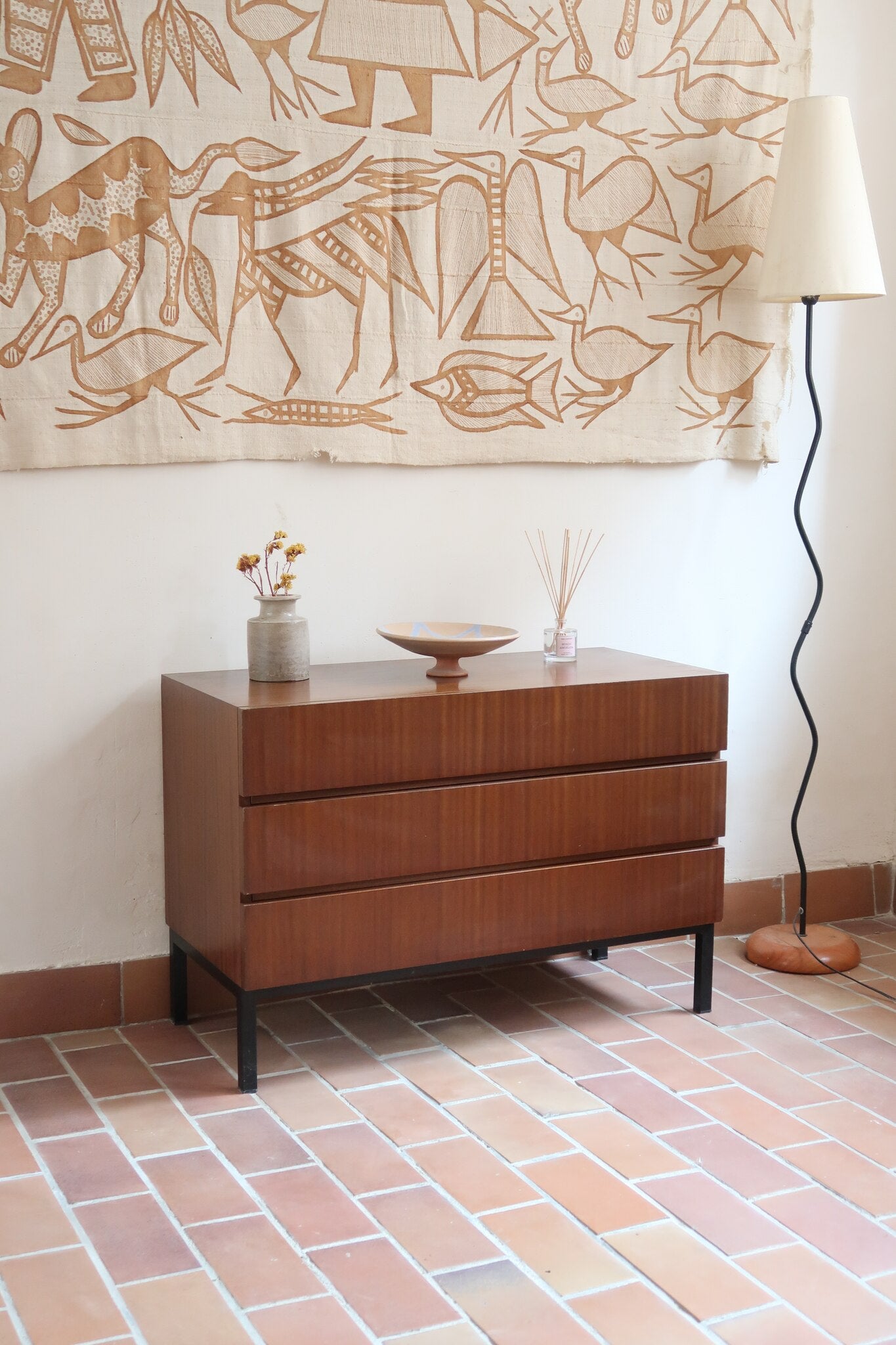 Commode vintage 3 tiroirs en teck années 60, façades pleines à prise de main creusée, piétement fin en métal laqué noir, style scandinave