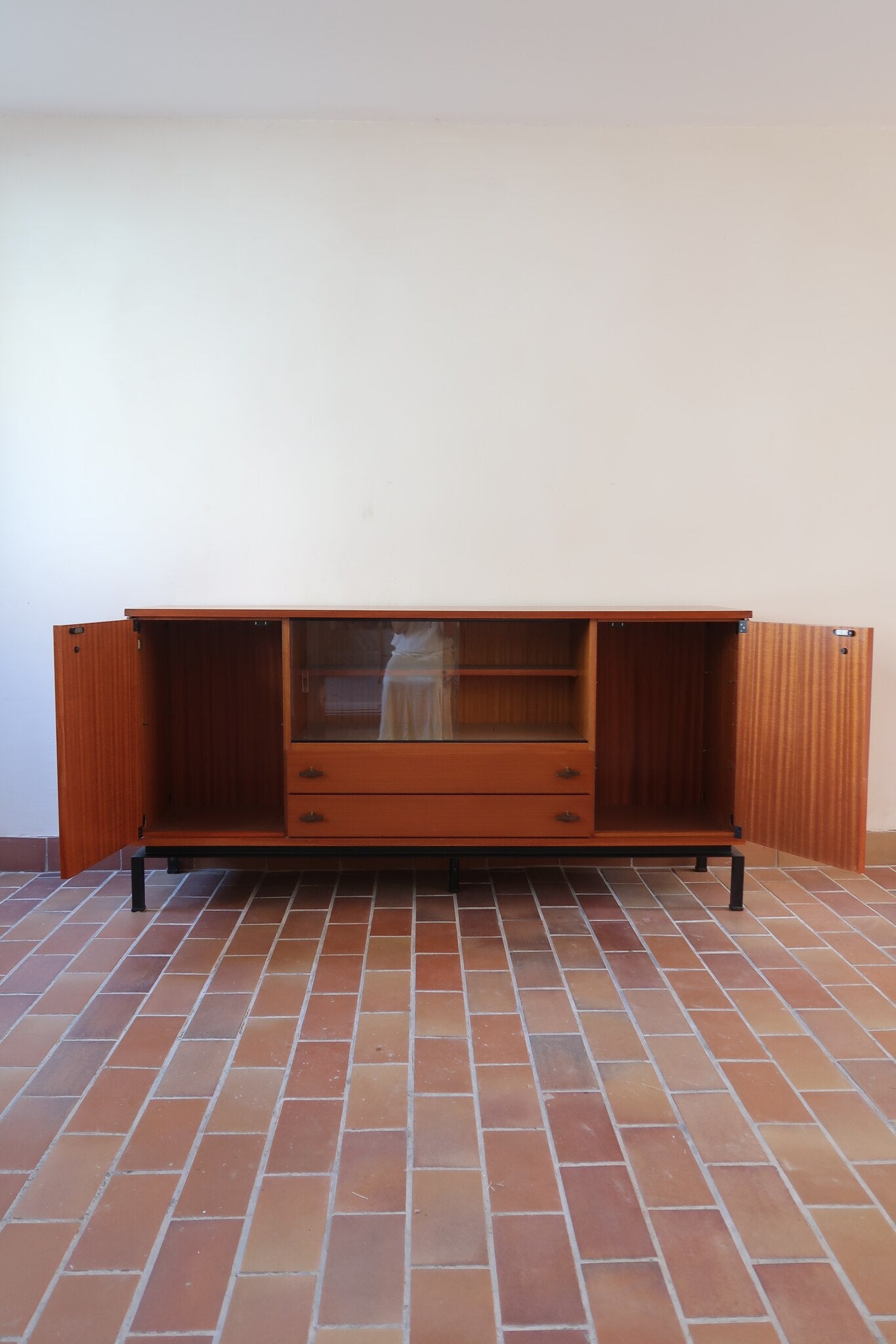 Enfilade vintage en teck années 60, deux portes pleines encadrant une vitrine centrale à portes coulissantes en verre, deux tiroirs, poignées navette métal, piétement métal laqué noir