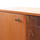 Enfilade vintage en teck années 60, deux portes pleines encadrant une vitrine centrale à portes coulissantes en verre, deux tiroirs, poignées navette métal, piétement métal laqué noir