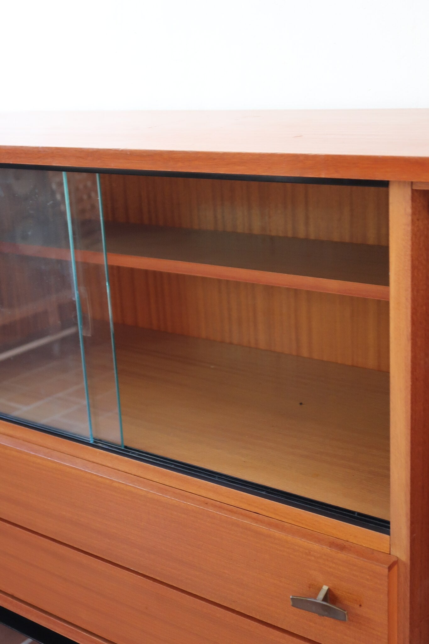 Enfilade vintage en teck années 60, deux portes pleines encadrant une vitrine centrale à portes coulissantes en verre, deux tiroirs, poignées navette métal, piétement métal laqué noir