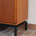 Enfilade vintage en teck années 60, deux portes pleines encadrant une vitrine centrale à portes coulissantes en verre, deux tiroirs, poignées navette métal, piétement métal laqué noir