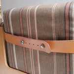 Fauteuil moderniste années 70 en bois massif clair sur roulettes avec coussins rayés bruns et terracotta.