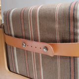 Fauteuil moderniste années 70 en bois massif clair sur roulettes avec coussins rayés bruns et terracotta.