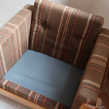 Fauteuil moderniste années 70 en bois massif clair sur roulettes avec coussins rayés bruns et terracotta.