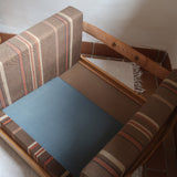 Fauteuil moderniste années 70 en bois massif clair sur roulettes avec coussins rayés bruns et terracotta.