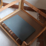 Fauteuil moderniste années 70 en bois massif clair sur roulettes avec coussins rayés bruns et terracotta.