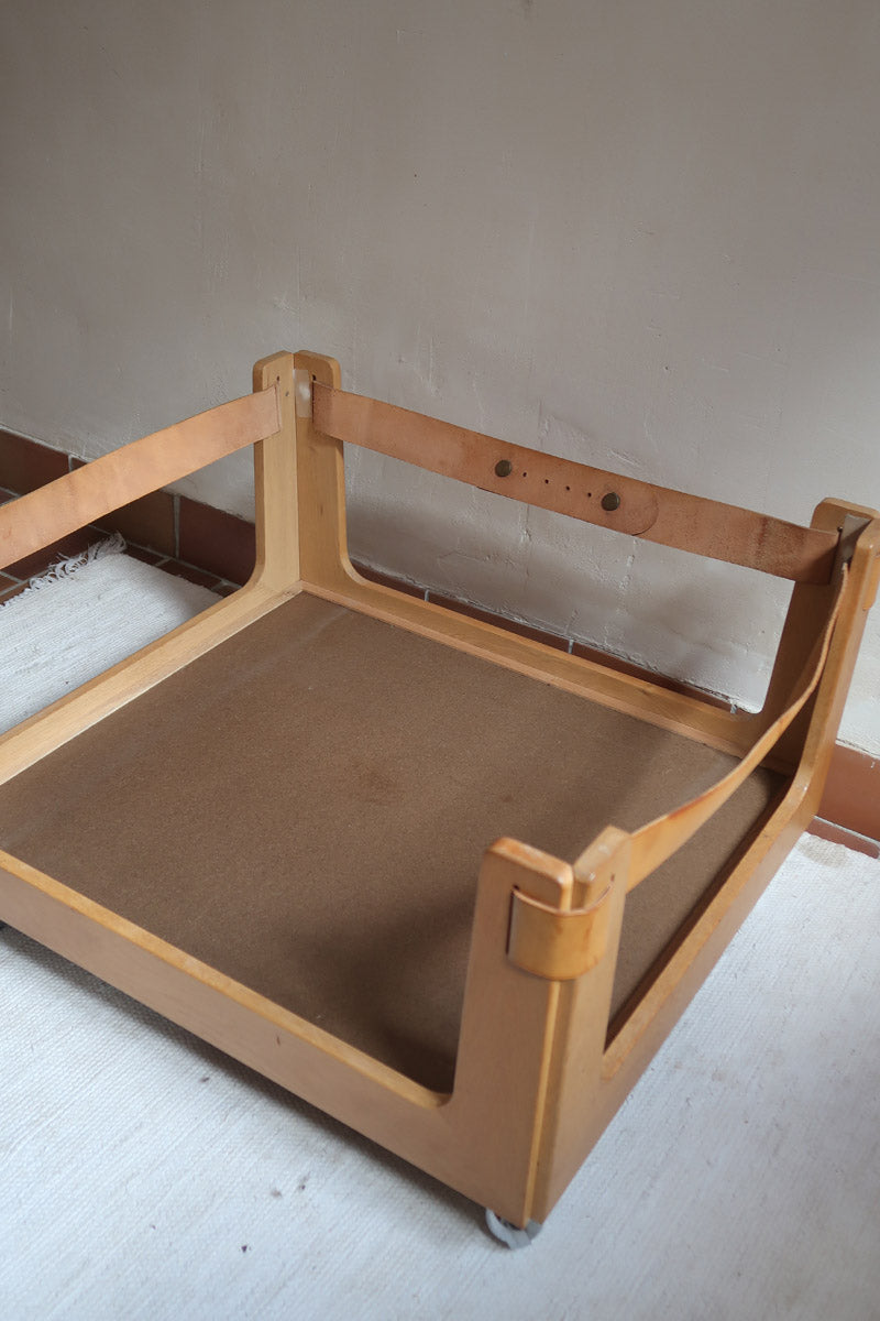 Fauteuil moderniste années 70 en bois massif clair sur roulettes avec coussins rayés bruns et terracotta.