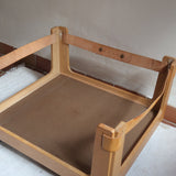 Fauteuil moderniste années 70 en bois massif clair sur roulettes avec coussins rayés bruns et terracotta.