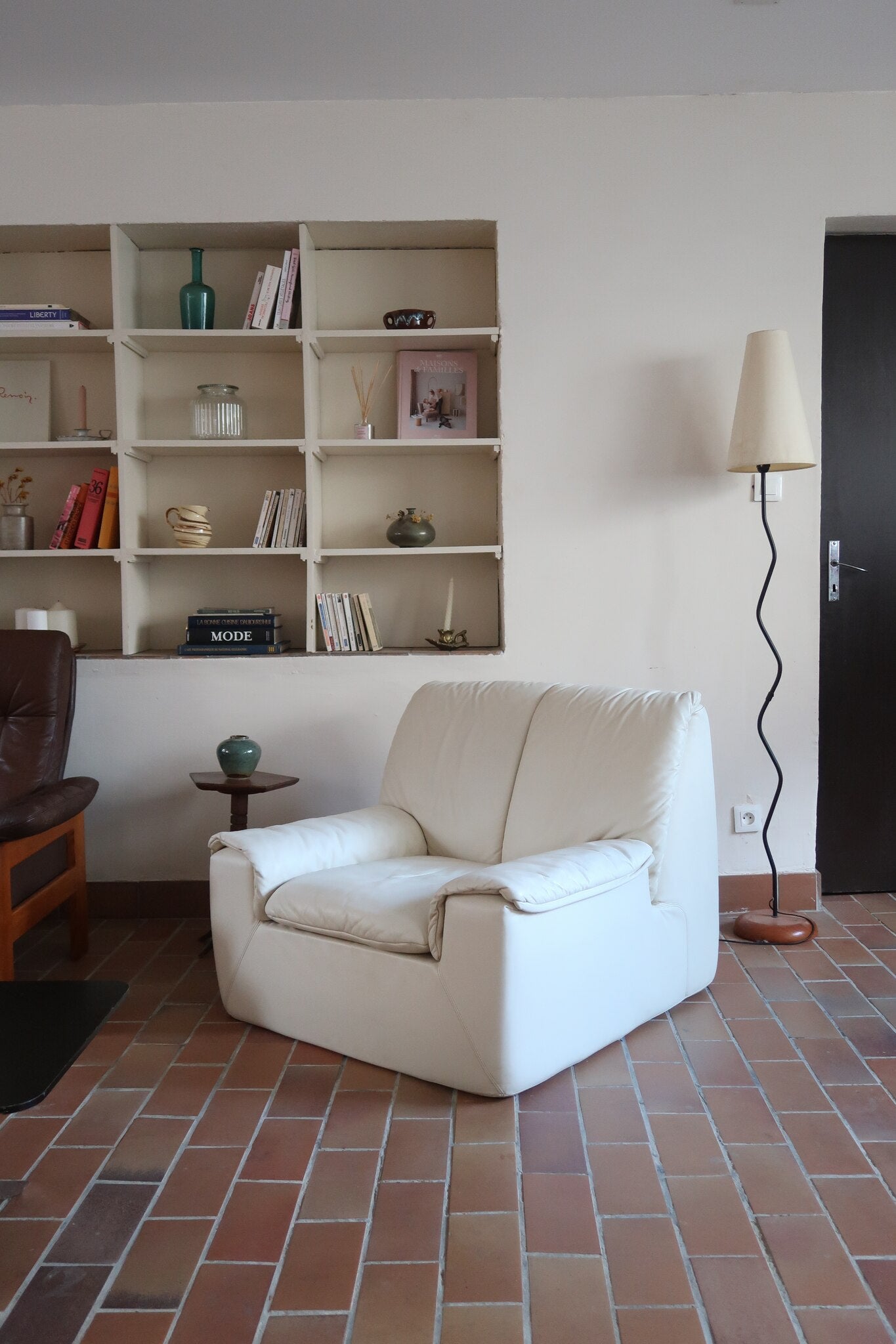 Fauteuil vintage Cinna en cuir crème années 70, étiquette d'origine cousue dans le dossier, accoudoirs et dossier en gros boudins de cuir, coussin d'assise, base pleine posée au sol sans pieds apparents