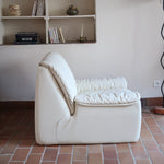 Fauteuil vintage Cinna en cuir crème années 70, étiquette d'origine cousue dans le dossier, accoudoirs et dossier en gros boudins de cuir, coussin d'assise, base pleine posée au sol sans pieds apparents