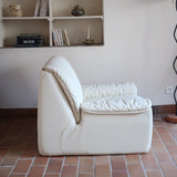 Fauteuil vintage Cinna en cuir crème années 70, étiquette d'origine cousue dans le dossier, accoudoirs et dossier en gros boudins de cuir, coussin d'assise, base pleine posée au sol sans pieds apparents