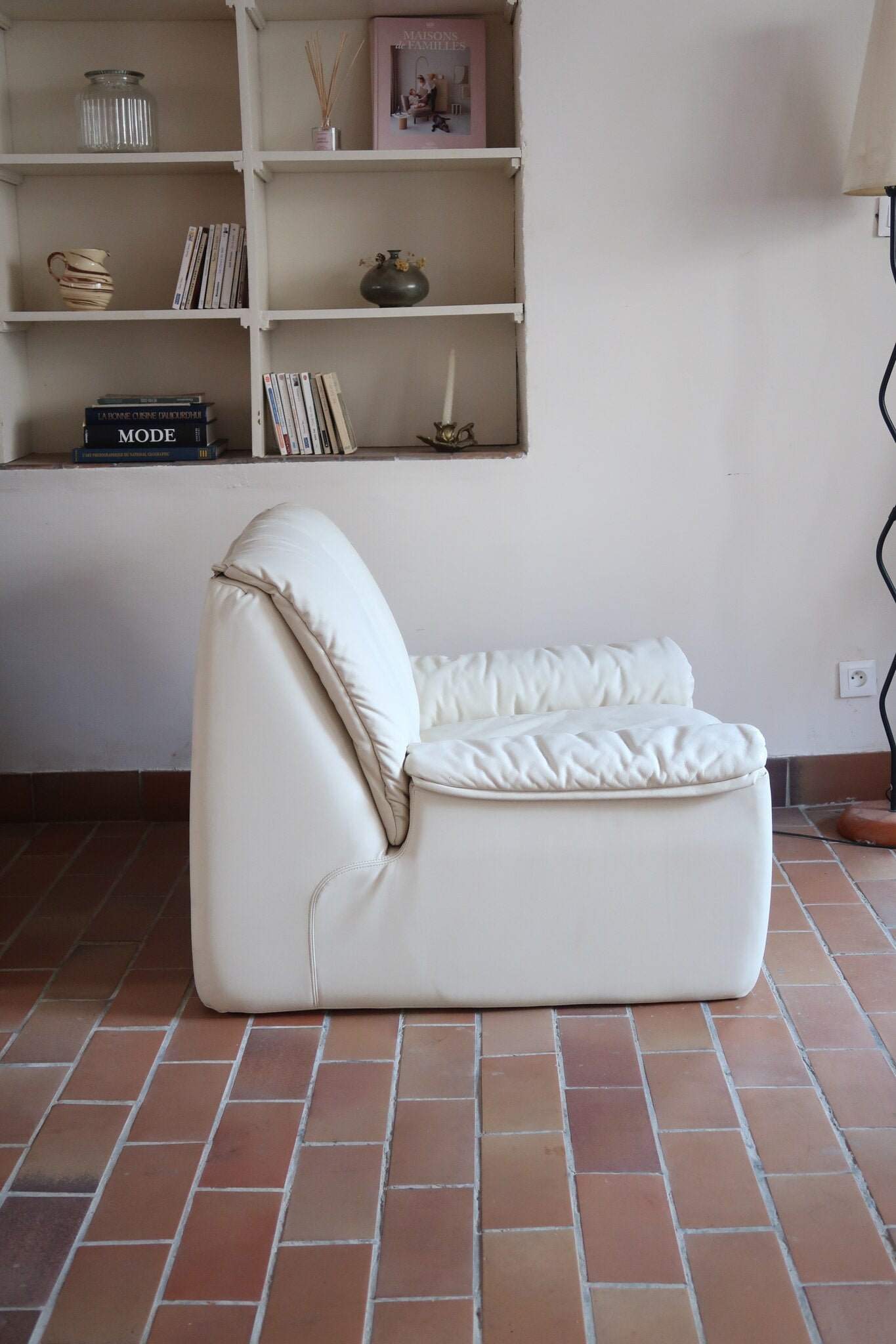 Fauteuil vintage Cinna en cuir crème années 70, étiquette d'origine cousue dans le dossier, accoudoirs et dossier en gros boudins de cuir, coussin d'assise, base pleine posée au sol sans pieds apparents