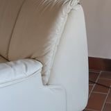 Fauteuil vintage Cinna en cuir crème années 70, étiquette d'origine cousue dans le dossier, accoudoirs et dossier en gros boudins de cuir, coussin d'assise, base pleine posée au sol sans pieds apparents