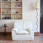 Fauteuil vintage Cinna en cuir crème années 70, étiquette d'origine cousue dans le dossier, accoudoirs et dossier en gros boudins de cuir, coussin d'assise, base pleine posée au sol sans pieds apparents