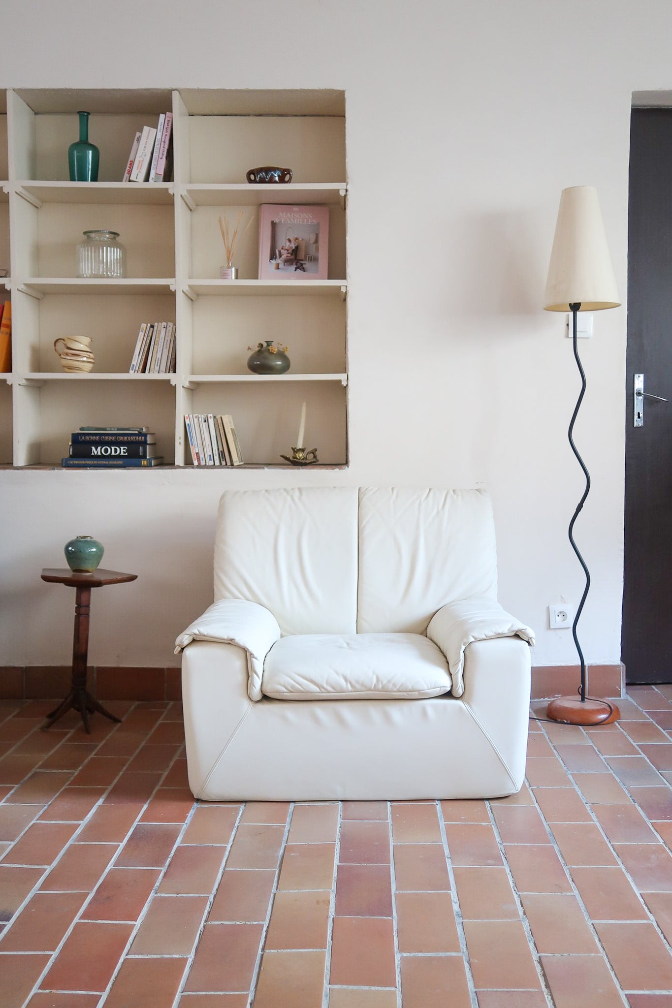 Fauteuil vintage Cinna en cuir crème années 70, étiquette d'origine cousue dans le dossier, accoudoirs et dossier en gros boudins de cuir, coussin d'assise, base pleine posée au sol sans pieds apparents