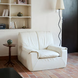 Fauteuil vintage Cinna en cuir crème années 70, étiquette d'origine cousue dans le dossier, accoudoirs et dossier en gros boudins de cuir, coussin d'assise, base pleine posée au sol sans pieds apparents
