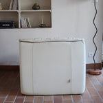 Fauteuil vintage Cinna en cuir crème années 70, étiquette d'origine cousue dans le dossier, accoudoirs et dossier en gros boudins de cuir, coussin d'assise, base pleine posée au sol sans pieds apparents