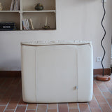 Fauteuil vintage Cinna en cuir crème années 70, étiquette d'origine cousue dans le dossier, accoudoirs et dossier en gros boudins de cuir, coussin d'assise, base pleine posée au sol sans pieds apparents