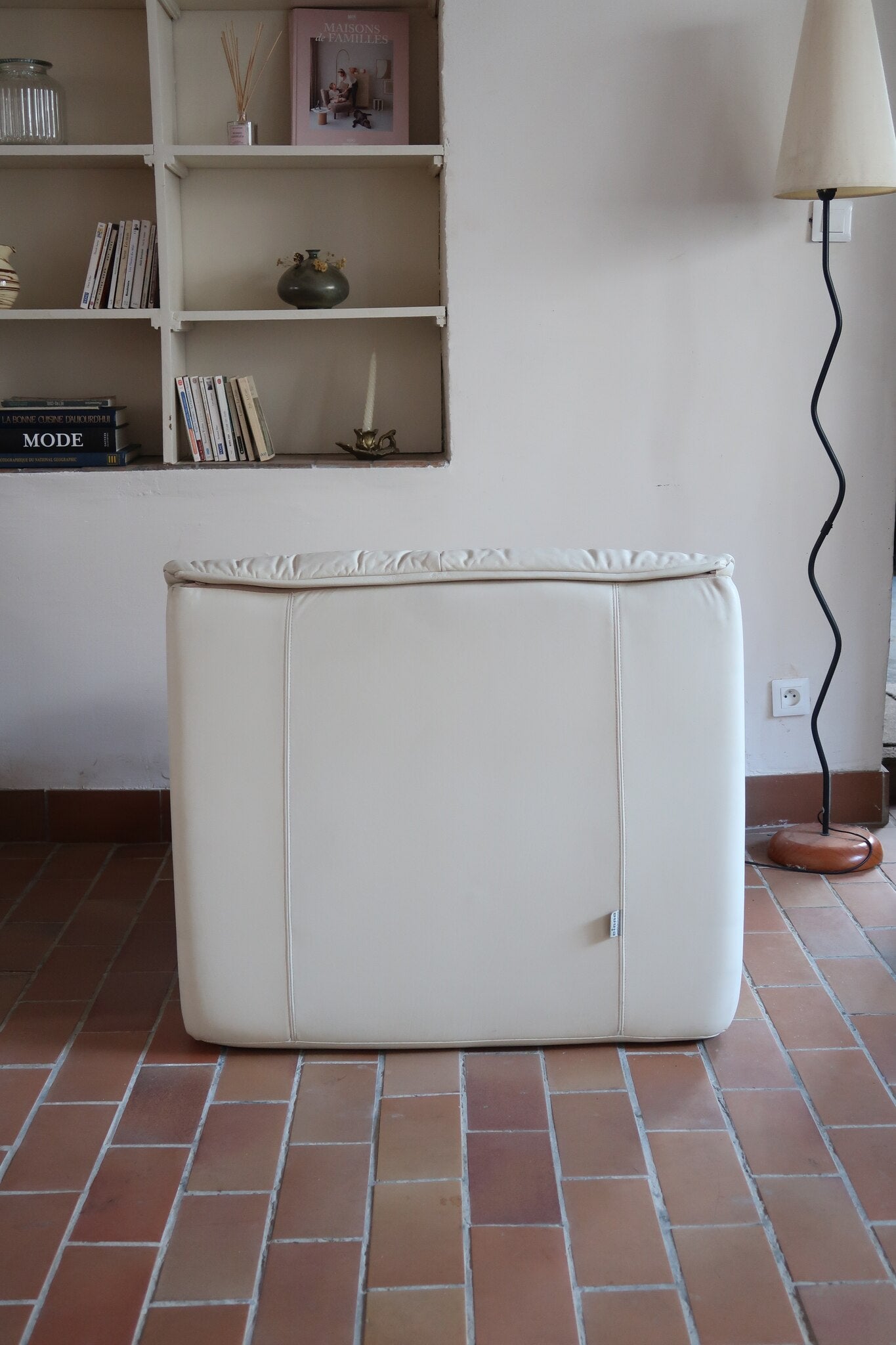 Fauteuil vintage Cinna en cuir crème années 70, étiquette d'origine cousue dans le dossier, accoudoirs et dossier en gros boudins de cuir, coussin d'assise, base pleine posée au sol sans pieds apparents