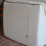 Fauteuil vintage Cinna en cuir crème années 70, étiquette d'origine cousue dans le dossier, accoudoirs et dossier en gros boudins de cuir, coussin d'assise, base pleine posée au sol sans pieds apparents