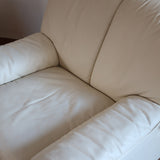 Fauteuil vintage Cinna en cuir crème années 70, étiquette d'origine cousue dans le dossier, accoudoirs et dossier en gros boudins de cuir, coussin d'assise, base pleine posée au sol sans pieds apparents