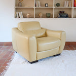 Fauteuil club vintage en cuir beige des années 80 avec accoudoirs larges et assise enveloppante.