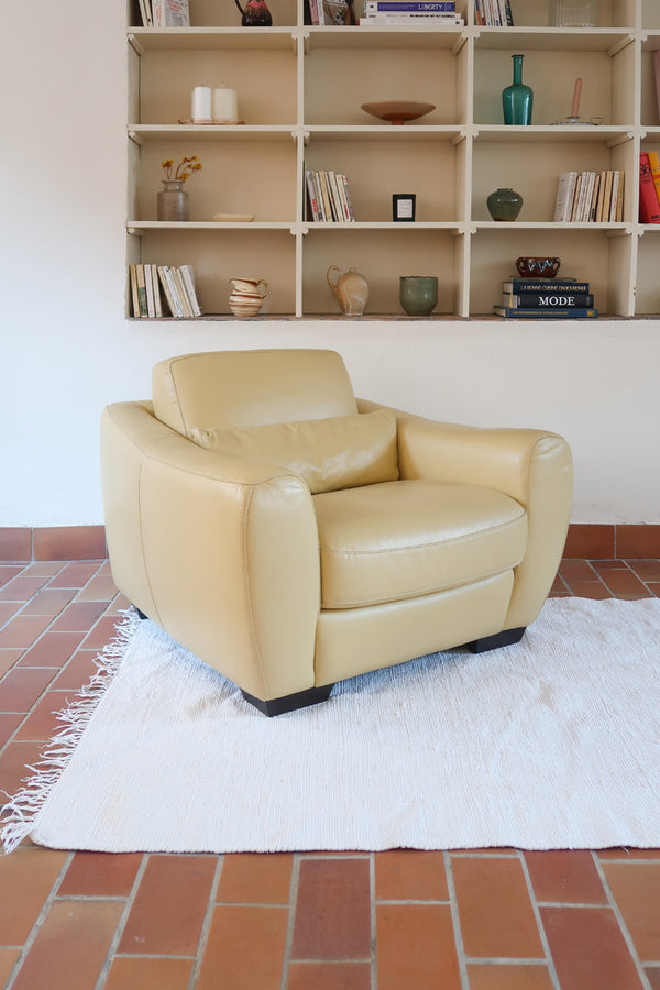 Fauteuil club vintage en cuir beige des années 80 avec accoudoirs larges et assise enveloppante.