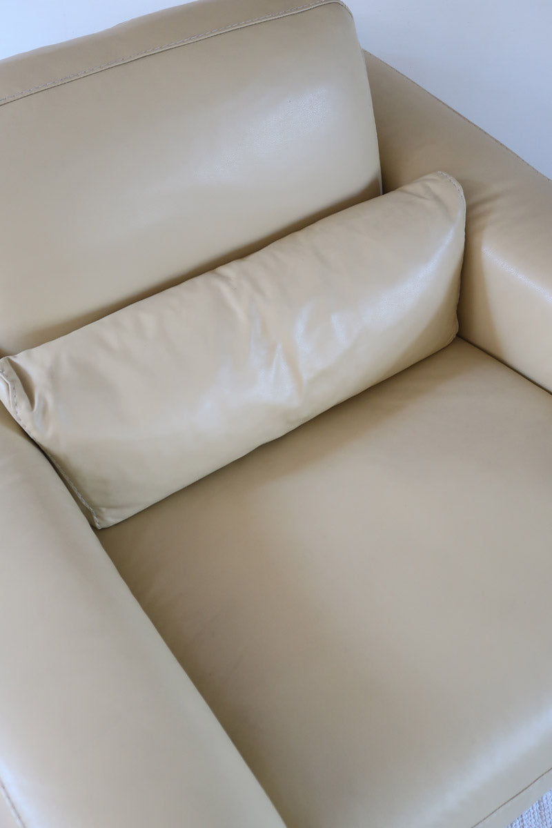 Fauteuil club vintage en cuir beige des années 80 avec accoudoirs larges et assise enveloppante.